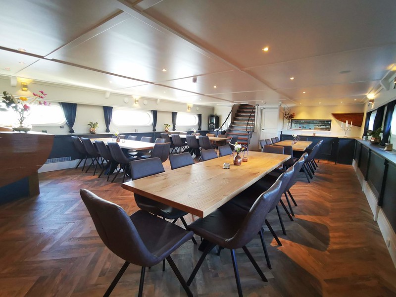 The elegant dining room of the Magnifique IV, located on the lower deck, offers breakfast and three-course dinners prepared by skilled chefs, visible through a glass wall.