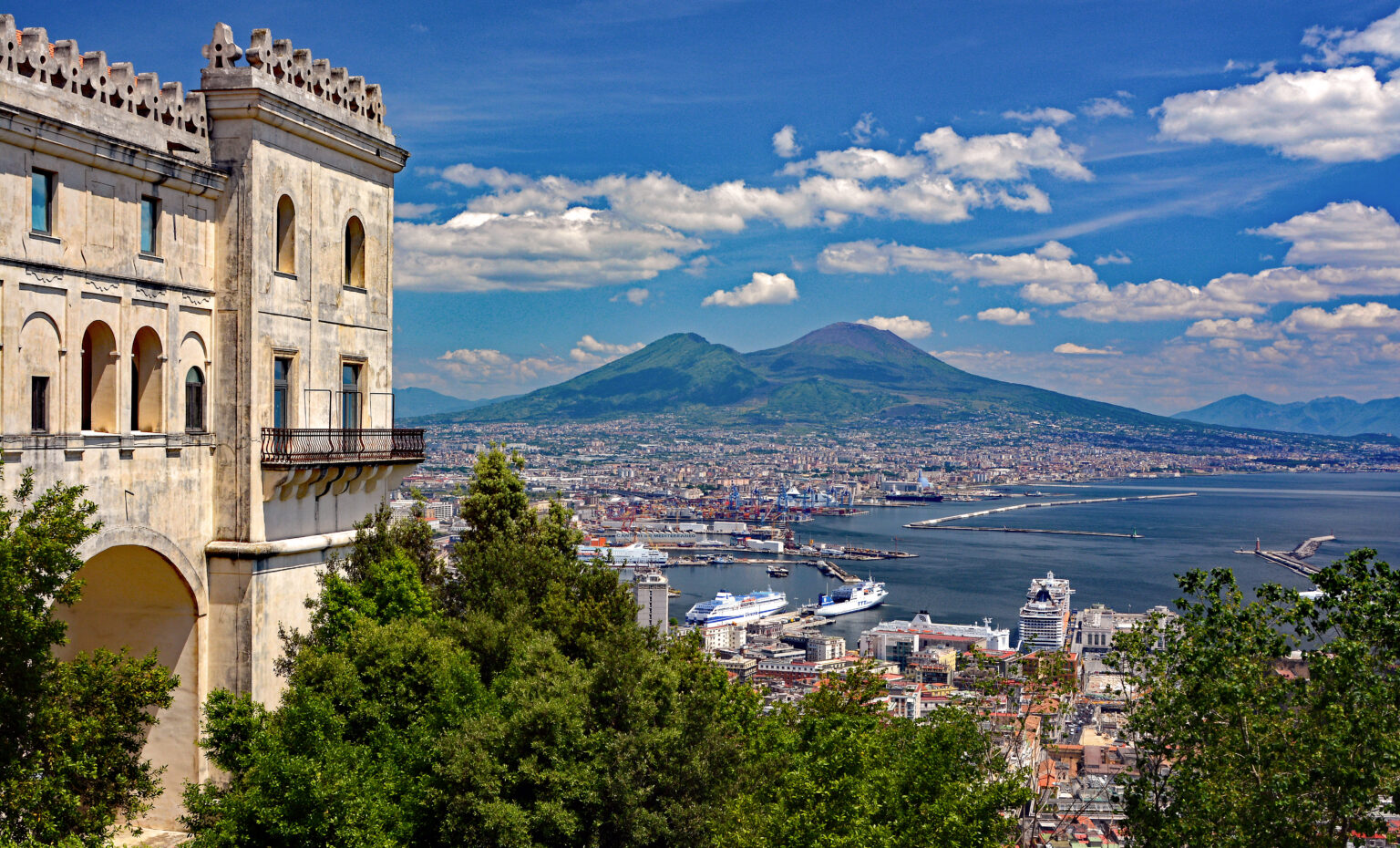 Overview of Naples, highlighting its coastal location and the imposing Mount Vesuvius in the distance.