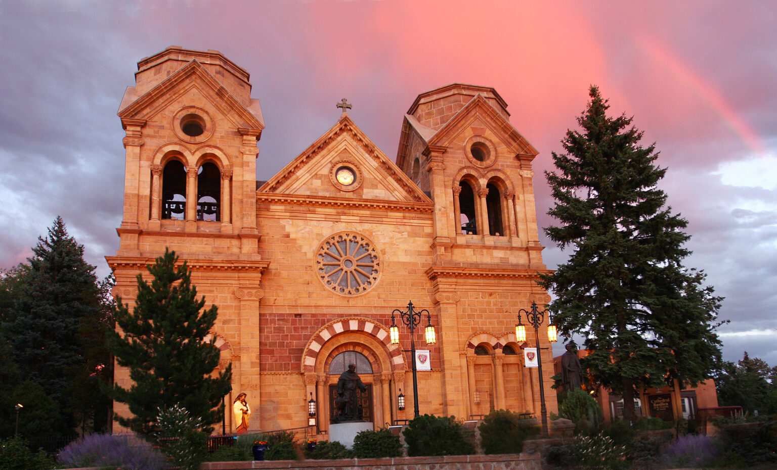 The Cathedral Basilica of St. Francis of Assisi in Santa Fe, New Mexico, stands as a prominent landmark with its Romanesque Revival architecture, featuring round arches, Corinthian columns, and a stunning rose window.