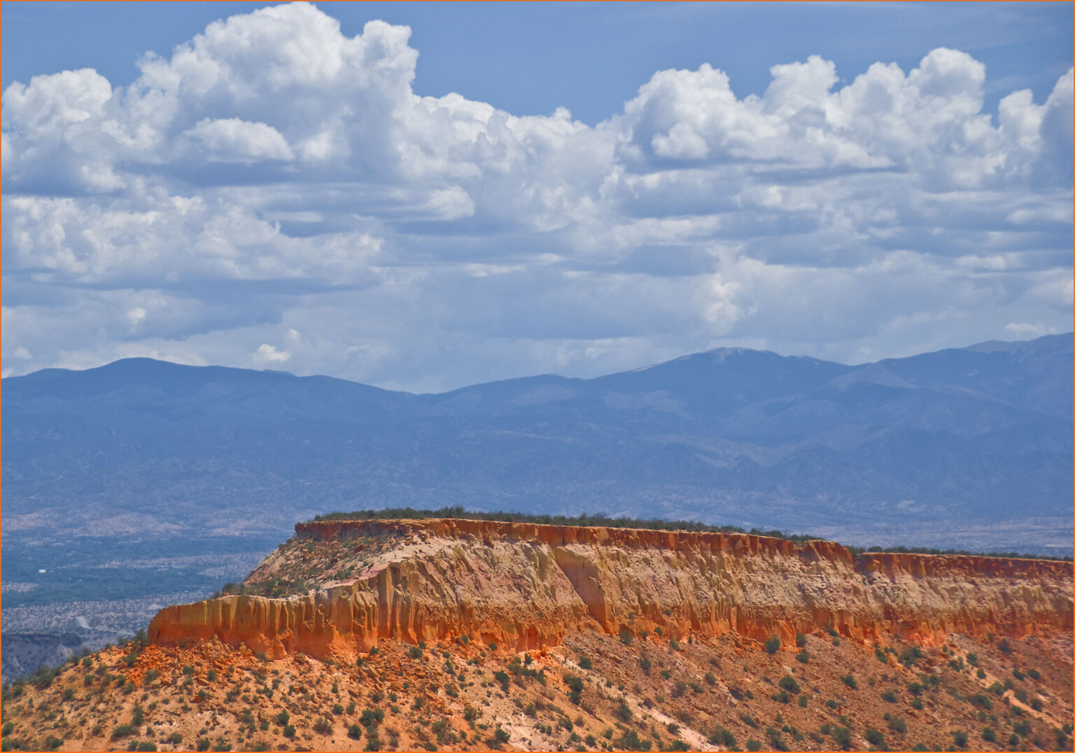 A panoramic view near Los Alamos, New Mexico, showcasing the stunning natural beauty of the surrounding mountains and canyons, with the Jemez Mountains visible in the distance