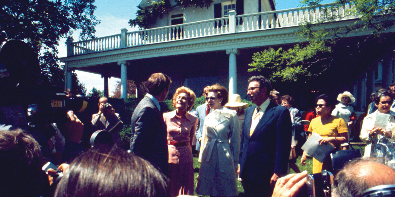 Philanthropist Enid A. Haupt and First Lady Patricia Nixon stand at the center of attention, surrounded by a crowd of people, cameras, and palpable excitement during the official opening ceremonies of River Farm as the American Horticultural Society headquarters on May 1, 1974.