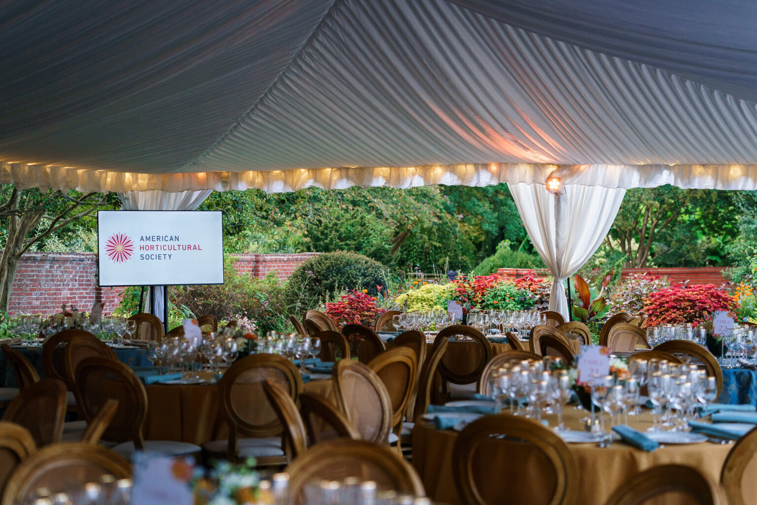 the elegant outdoor table setting under the canopy and surrounded by beautiful gardens of the American Horticultural Society's Gala at River Farm