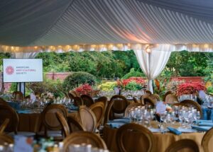 Round tables clustered together under a tent, ready for a party.