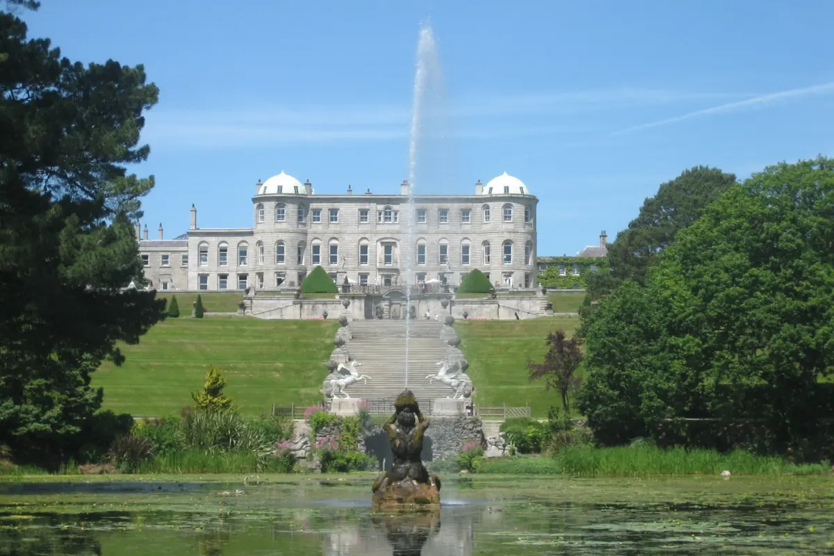 White stone historic building with a large fountain in a formal garden in Ireland