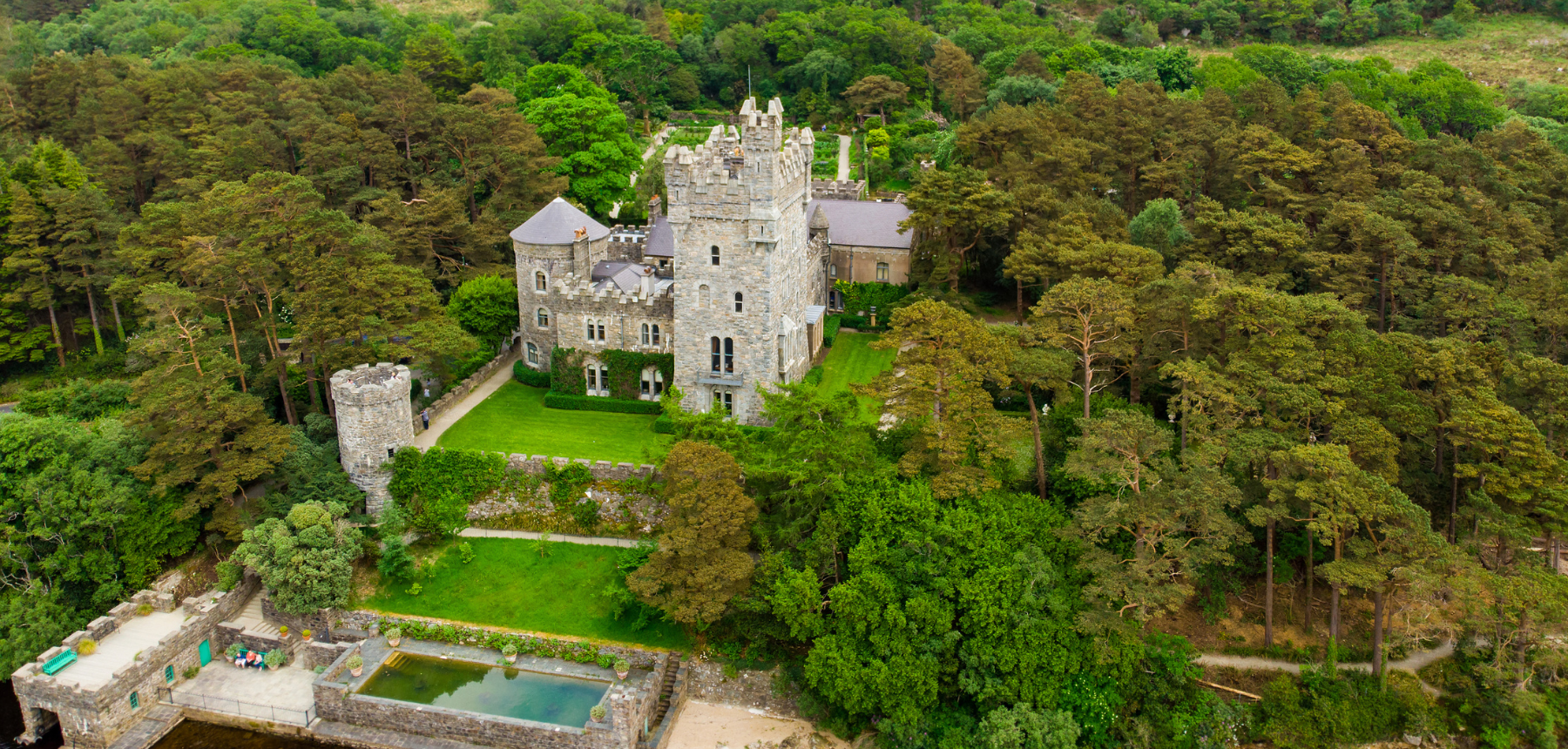 Stone castle surrounded by green lawns and green trees.