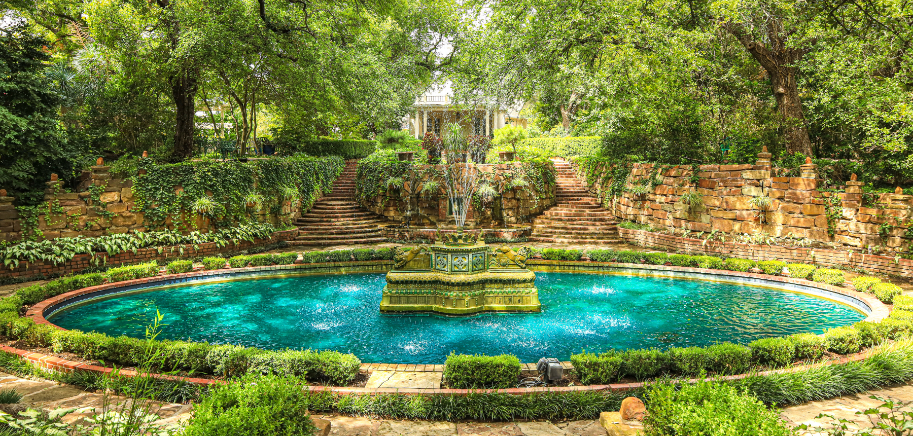 A round stone fountain with bright blue water in a garden
