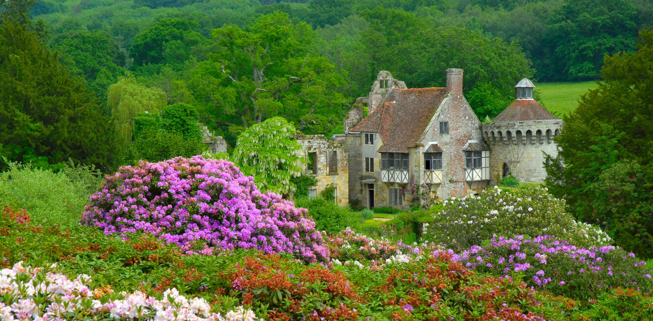 Old English castle surrounded by plenty of trees and flowers
