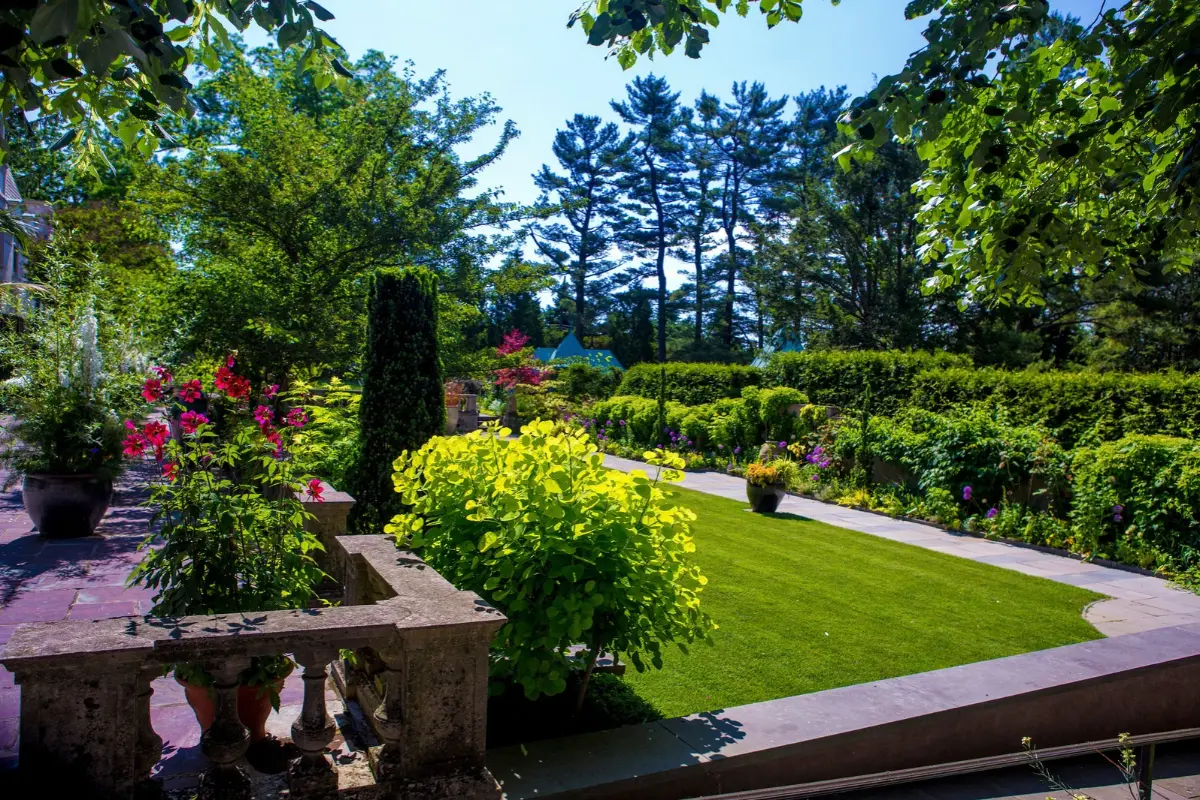 A terrace with white and red blooming plants in a lush garden at Chanticleer.